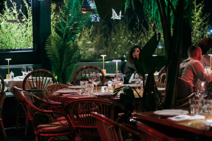 Salle du restaurant COBA : fauteuils en rotin, tables dressées, végétation